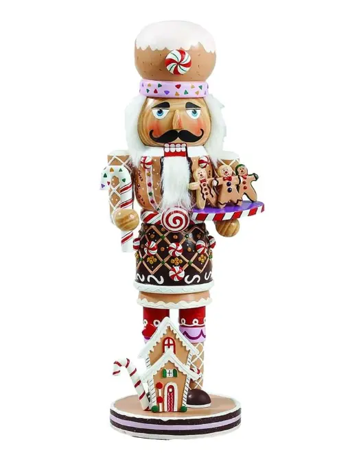 gingerbread nutcracker figurine decorated with icing patterns, candy details, gingerbread men tray, and a small gingerbread house base on white background