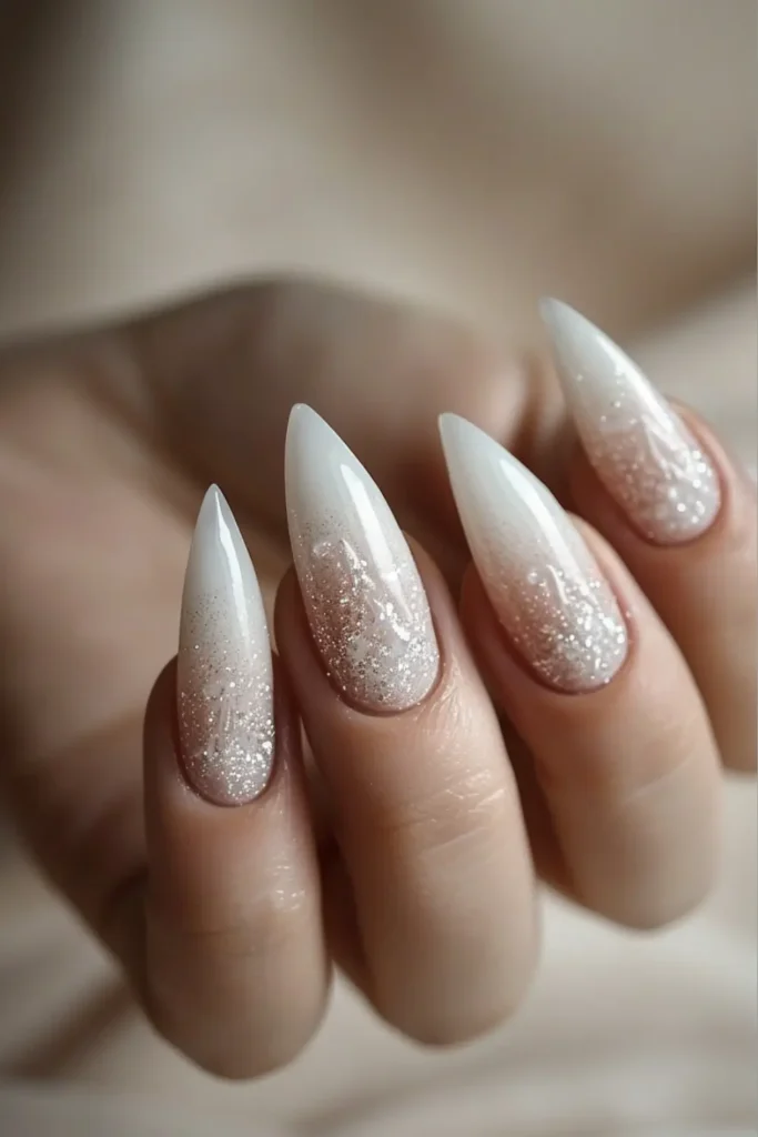 White frosted stiletto nails with icy glitter ombré, winter New Year’s Eve nails.