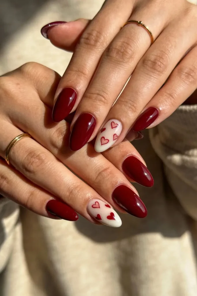 Burgundy almond Valentine’s Day nails with heart accent and glossy finish